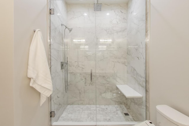 bathroom with a shower with shower door and toilet