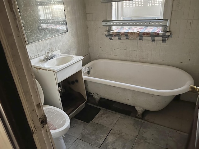 bathroom featuring a freestanding tub, toilet, tile walls, and vanity