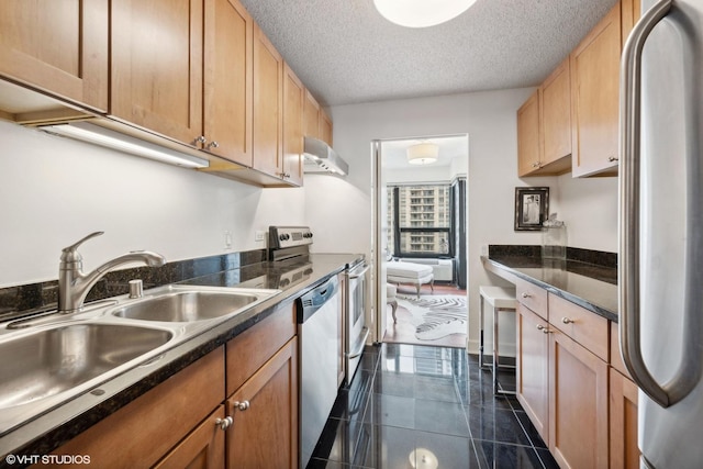 kitchen with sink, dark tile patterned floors, stainless steel appliances, and a textured ceiling