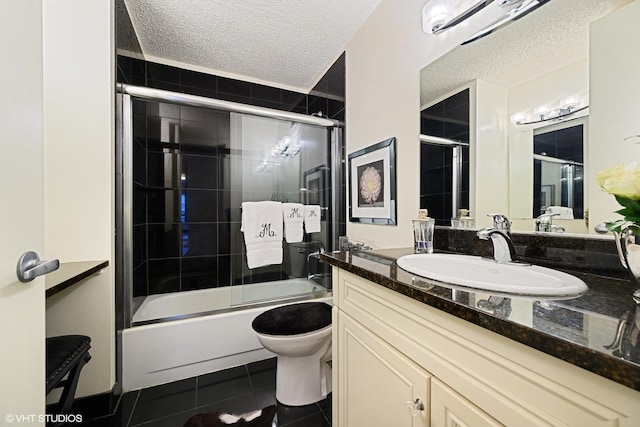 full bathroom with combined bath / shower with glass door, vanity, toilet, tile patterned floors, and a textured ceiling