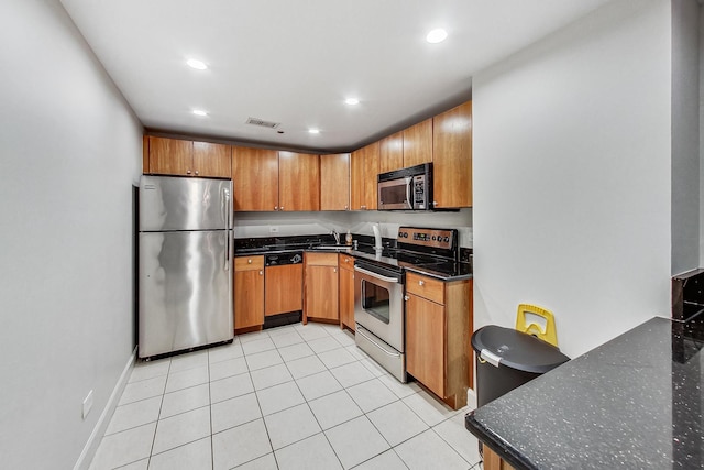 kitchen featuring light tile patterned flooring, appliances with stainless steel finishes, sink, and dark stone countertops