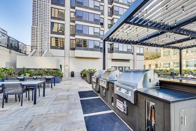 view of patio featuring exterior kitchen, grilling area, and a pergola