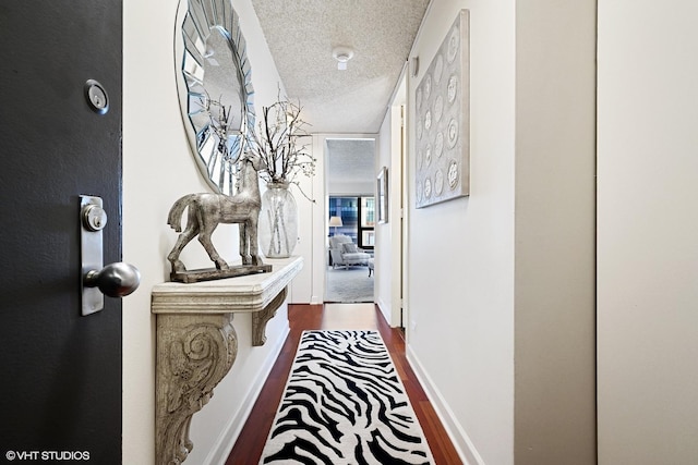 corridor with hardwood / wood-style floors and a textured ceiling