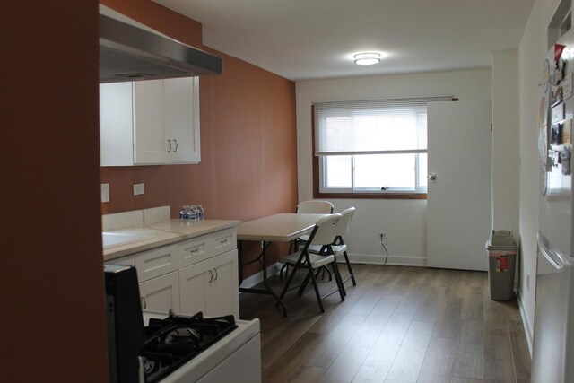17544 Roy St, Lansing, IL 60438 - kitchen with range hood, white cabinetry, hardwood / wood-style flooring, light stone counters, and gas range