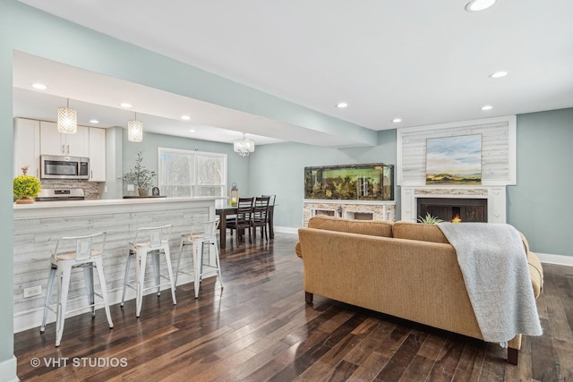 living area with a large fireplace, baseboards, dark wood-type flooring, and recessed lighting