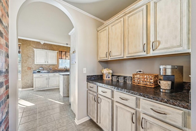 kitchen featuring pendant lighting, dark stone countertops, ornamental molding, light tile patterned flooring, and light brown cabinets