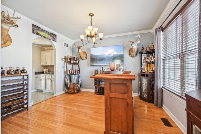 dining area with ornamental molding, a wealth of natural light, a notable chandelier, and light wood-type flooring