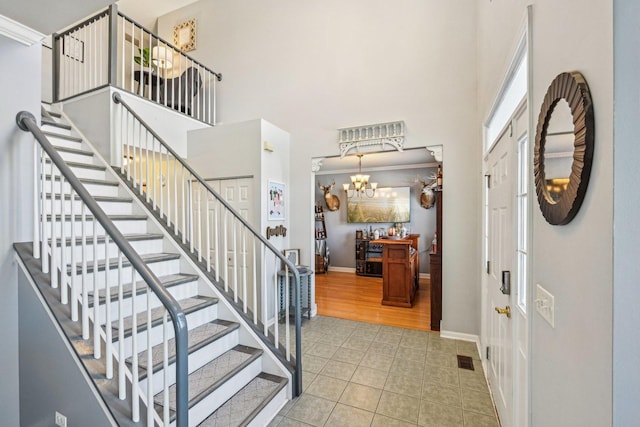 foyer with a high ceiling, light wood-type flooring, and an inviting chandelier