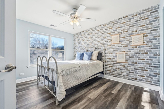 bedroom featuring dark hardwood / wood-style flooring, ceiling fan, and brick wall