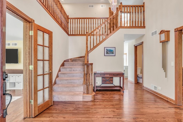 staircase featuring a towering ceiling, hardwood / wood-style floors, and french doors