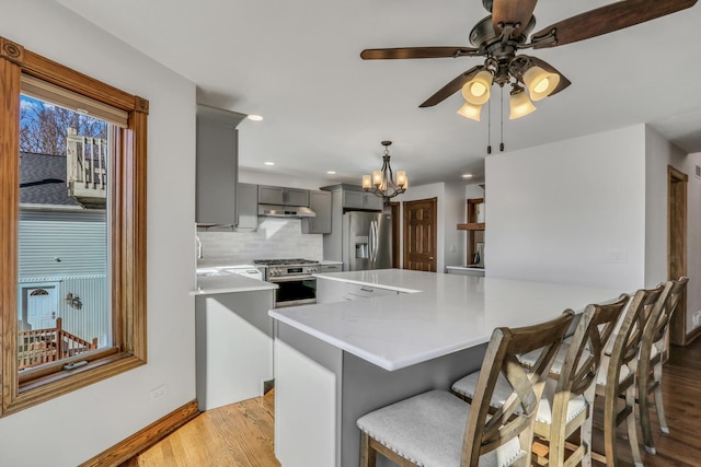 kitchen featuring appliances with stainless steel finishes, kitchen peninsula, hanging light fixtures, and gray cabinetry