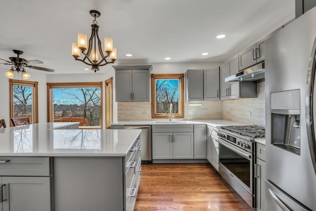 kitchen featuring pendant lighting, sink, hardwood / wood-style flooring, appliances with stainless steel finishes, and gray cabinetry