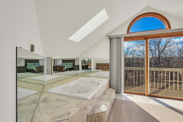 bathroom featuring tile patterned flooring, a tub to relax in, and vaulted ceiling with skylight