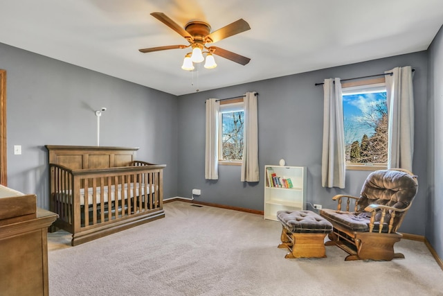 carpeted bedroom with ceiling fan and a crib