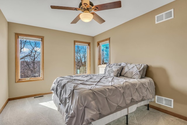 bedroom featuring ceiling fan, multiple windows, and light carpet