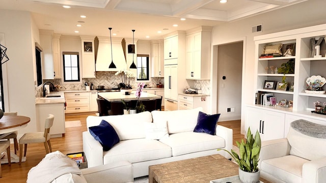 living area featuring coffered ceiling, light wood-type flooring, visible vents, and recessed lighting