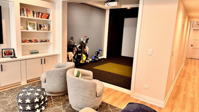 interior space with baseboards, golf simulator, wood finished floors, and built in features