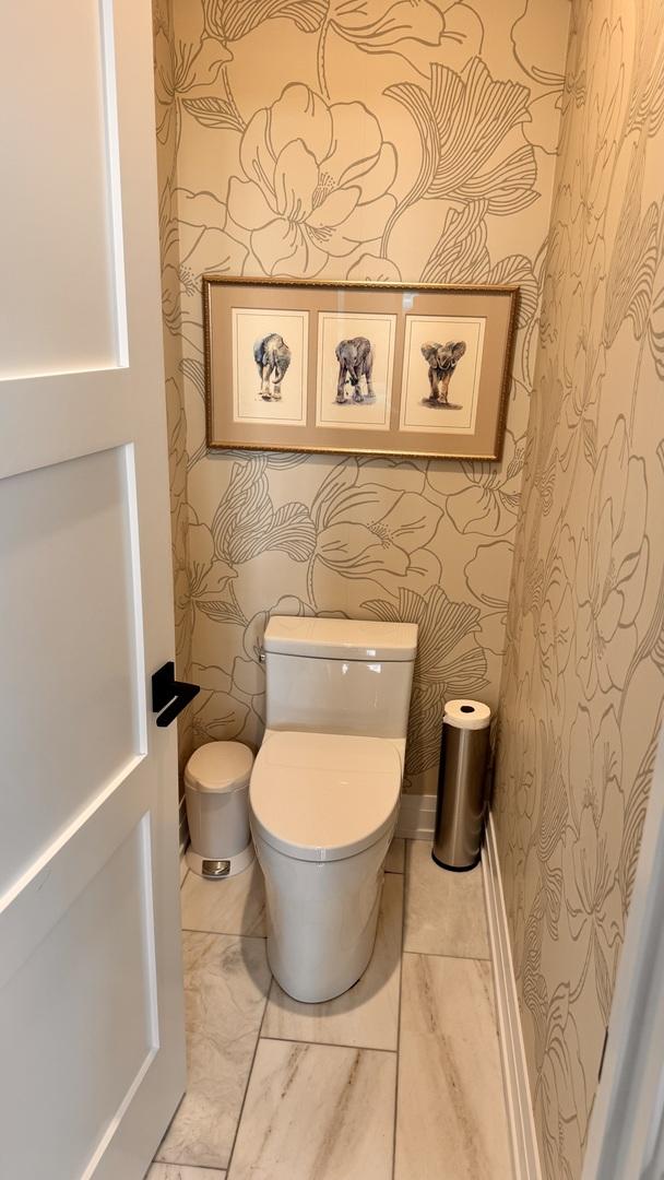 bathroom featuring baseboards, toilet, and wallpapered walls