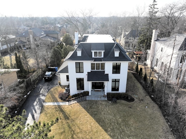 view of front facade with a chimney, a front lawn, and roof with shingles