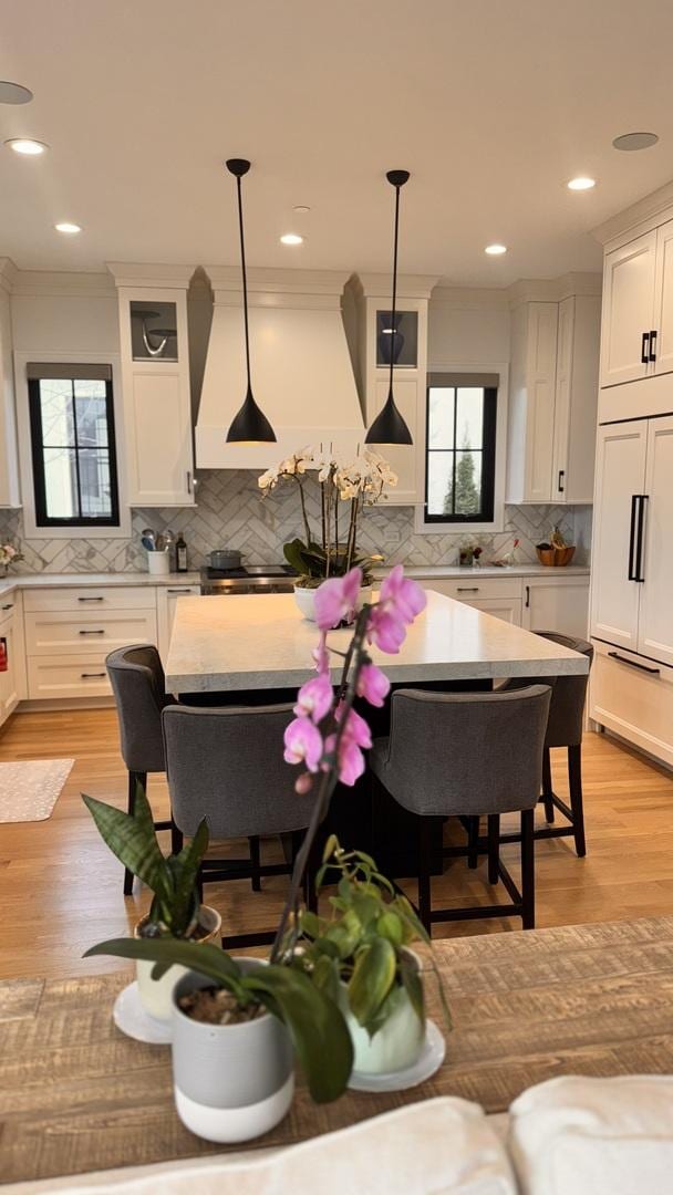 kitchen with paneled fridge, light wood finished floors, light countertops, and white cabinets