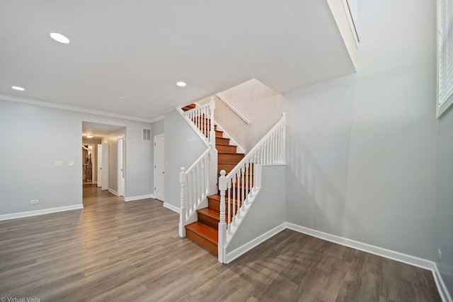 staircase with ornamental molding and hardwood / wood-style floors