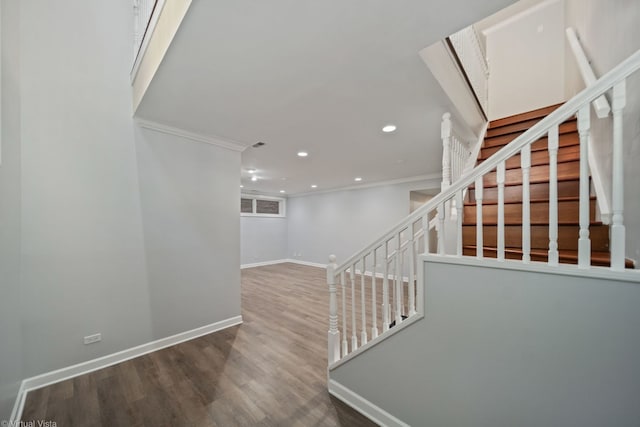 staircase with wood-type flooring and ornamental molding