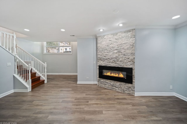 unfurnished living room with crown molding, wood-type flooring, and a stone fireplace