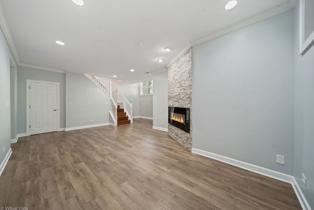 unfurnished living room with crown molding, a stone fireplace, and hardwood / wood-style floors