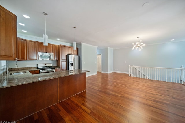 kitchen with sink, stainless steel appliances, decorative light fixtures, kitchen peninsula, and dark stone counters