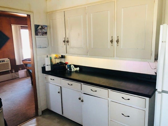 kitchen with white refrigerator, decorative backsplash, and white cabinets