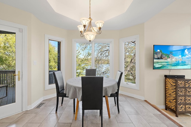 tiled dining space featuring an inviting chandelier and a tray ceiling