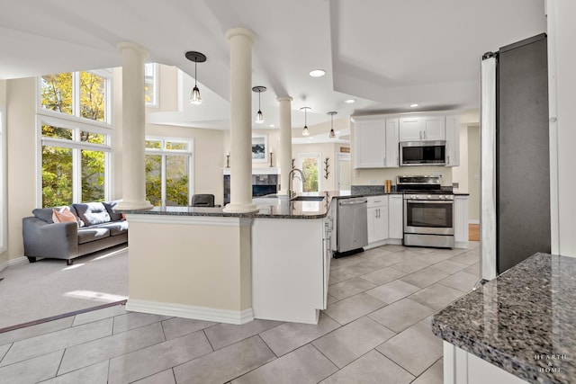 kitchen featuring appliances with stainless steel finishes, white cabinetry, decorative light fixtures, kitchen peninsula, and ornate columns