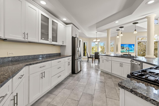 kitchen with white cabinets, appliances with stainless steel finishes, decorative light fixtures, and ornate columns