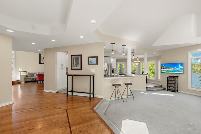 kitchen with stainless steel fridge with ice dispenser, hanging light fixtures, a kitchen breakfast bar, kitchen peninsula, and white cabinets