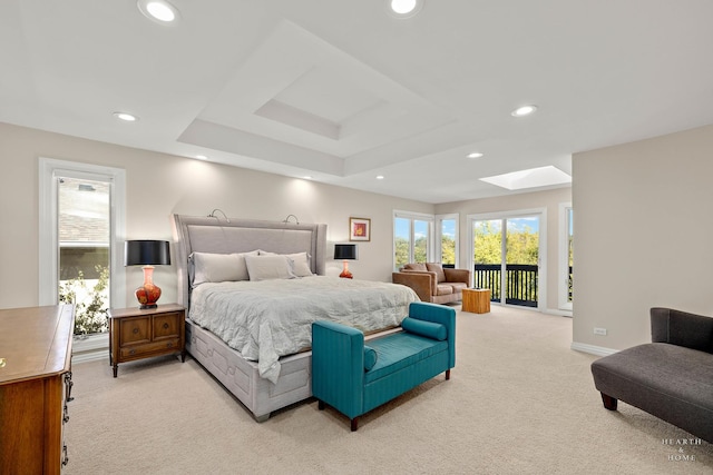 carpeted bedroom with access to exterior, a skylight, and a raised ceiling