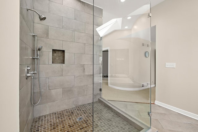 bathroom featuring tiled shower, a skylight, and tile patterned flooring