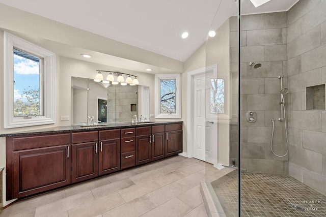 bathroom featuring vanity, vaulted ceiling, a tile shower, and tile patterned floors