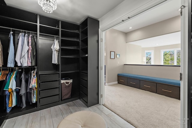 walk in closet featuring a notable chandelier and carpet flooring