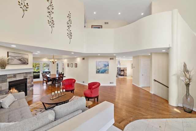 living room featuring a high ceiling, a stone fireplace, and light hardwood / wood-style floors