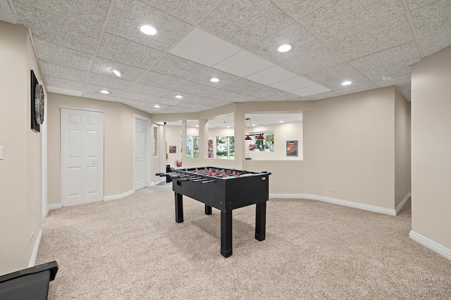 recreation room featuring a drop ceiling and carpet floors