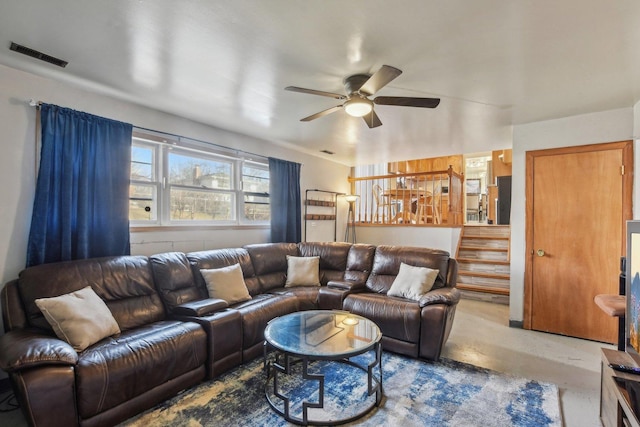 living room featuring visible vents, concrete flooring, ceiling fan, and stairway