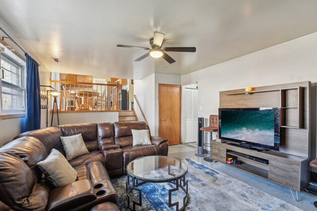 living area featuring stairway, a ceiling fan, concrete flooring, and visible vents