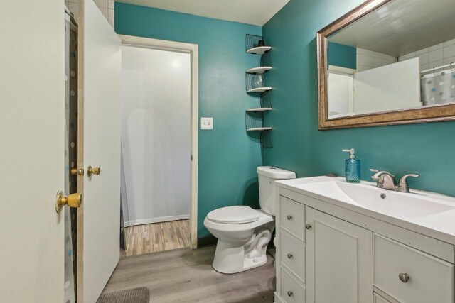 full bathroom with toilet, wood finished floors, and vanity