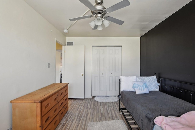 bedroom featuring a closet, visible vents, a ceiling fan, and wood finished floors