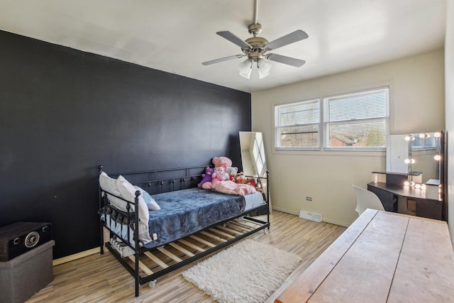 bedroom with a ceiling fan, visible vents, wood finished floors, and baseboards