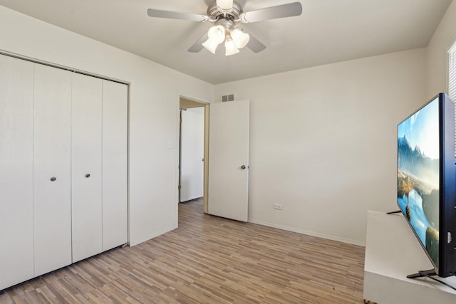 unfurnished bedroom featuring visible vents, baseboards, ceiling fan, light wood-style floors, and a closet