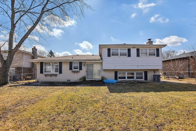 tri-level home with fence, central AC unit, a chimney, a front lawn, and brick siding