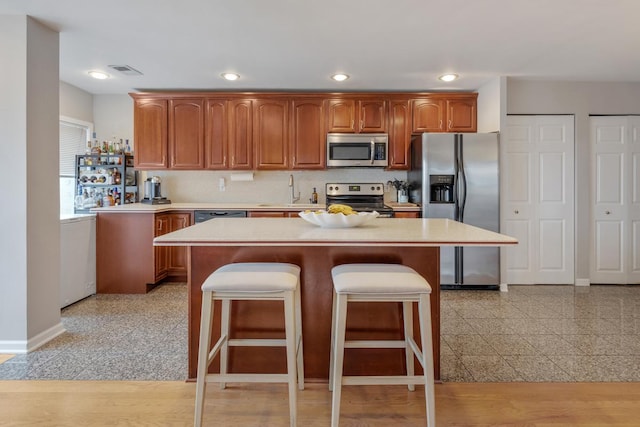 kitchen with a kitchen island, appliances with stainless steel finishes, sink, and a breakfast bar area