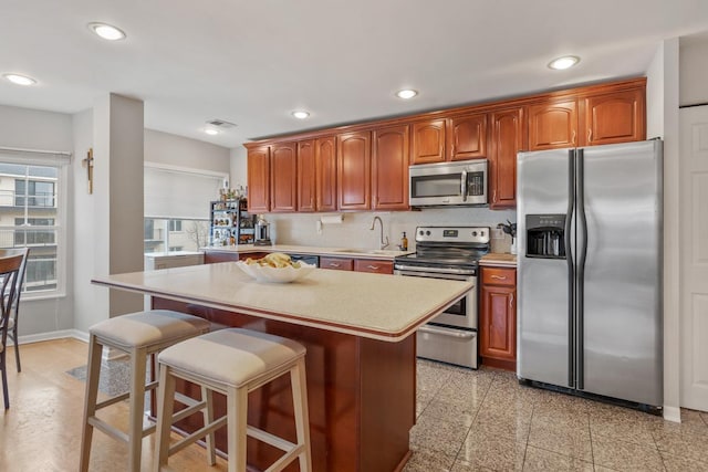 kitchen featuring a kitchen island, appliances with stainless steel finishes, sink, backsplash, and a kitchen breakfast bar