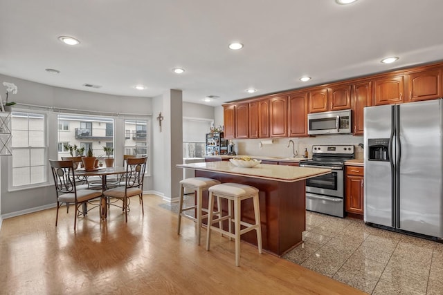 kitchen with a breakfast bar, sink, backsplash, a center island, and stainless steel appliances